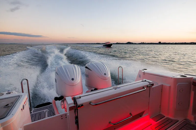 Slide: The Image of 2025 Solara S-310 SB boat cruising at sunset with dual engines, creating a wake. - 21