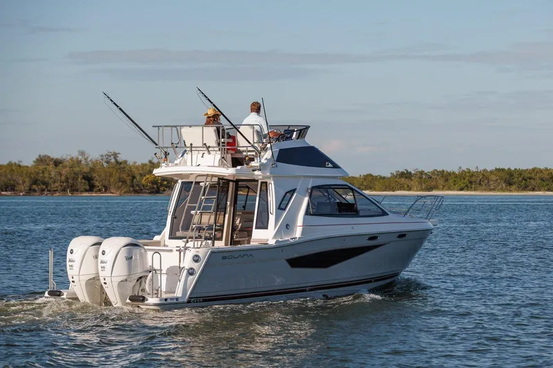 Slide: The Image of 2025 Solara S-310 SB boat cruising on a calm lake with two people onboard. - 23