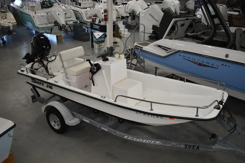 Slide: The Image of 2011 Carolina Skiff J16 boat on trailer in showroom, surrounded by other boats. - 6