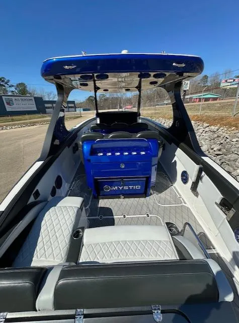 Slide: The Image of 2019 Mystic Powerboats M4200 interior with blue console and seating, docked outdoors. - 5