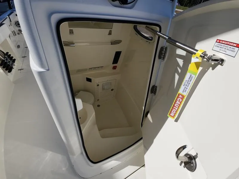 Slide: The Image of 2025 Cobia 265 Center Console boat interior cabin with open door and caution label. - 17