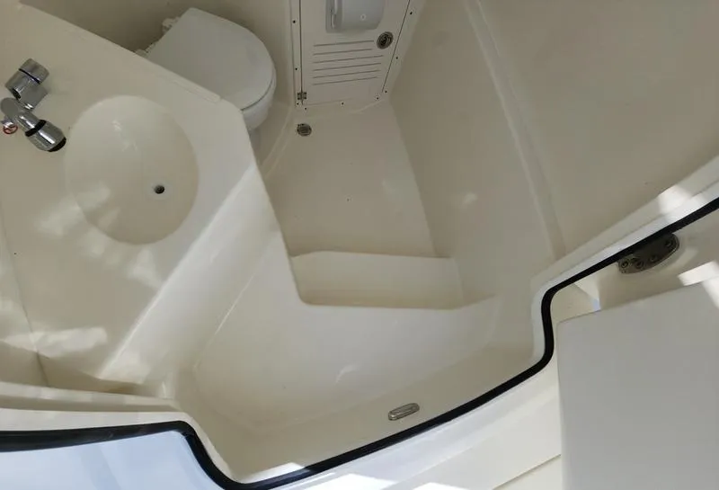 Slide: The Image of Interior of 2025 Cobia 265 Center Console boat, featuring a compact bathroom area. - 20