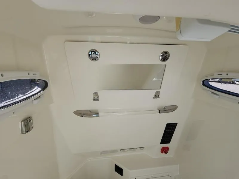 Slide: The Image of 2025 Cobia 265 Center Console cabin interior with storage compartment and portholes. - 24