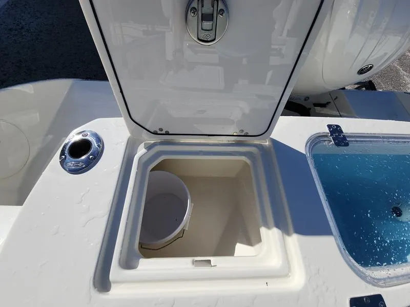 Slide: The Image of 2025 Cobia 265 Center Console boat storage compartment with open lid and bucket. - 28