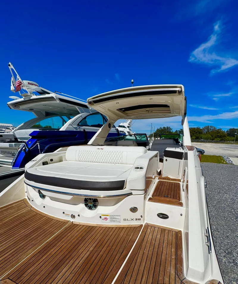 Slide: The Image of 2019 Sea Ray SLX 310 boat with teak deck and luxurious seating under a clear blue sky. - 12