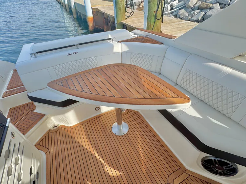 Slide: The Image of 2019 Sea Ray SLX 310 boat with teak deck and triangular table, docked by the water. - 13