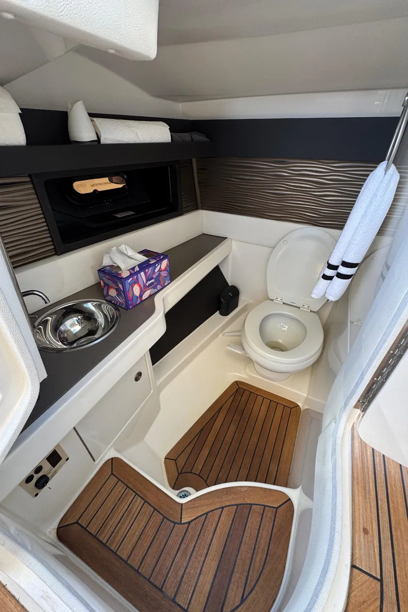Slide: The Image of 2019 Sea Ray SLX 310 boat bathroom with sink, toilet, and wooden flooring. - 24