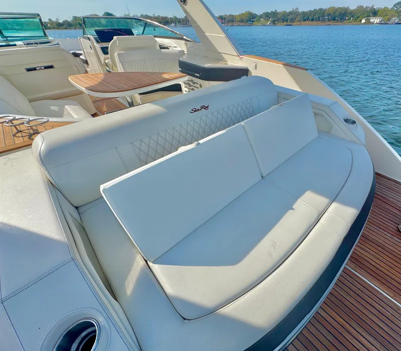 Slide: The Image of 2019 Sea Ray SLX 310 boat interior with white seating and wooden deck, on a sunny day. - 26