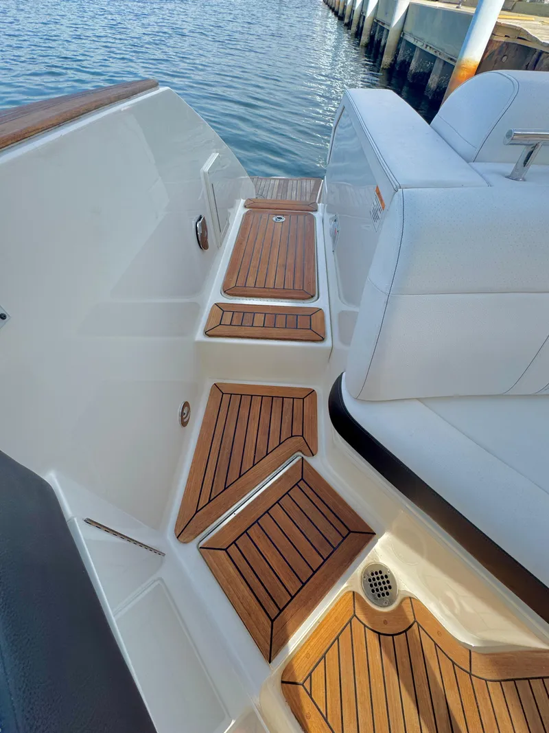 Slide: The Image of 2019 Sea Ray SLX 310 boat with teak deck, docked by the water. - 34