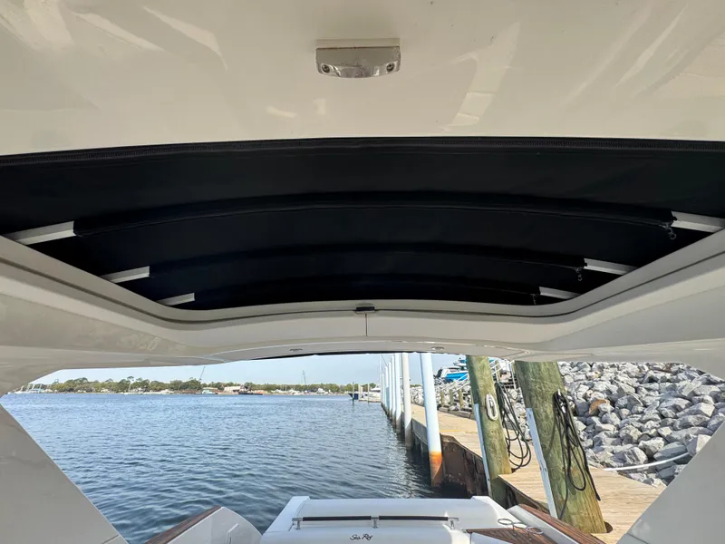 Slide: The Image of 2019 Sea Ray SLX 310 boat with open sunroof, docked by a scenic waterfront. - 35