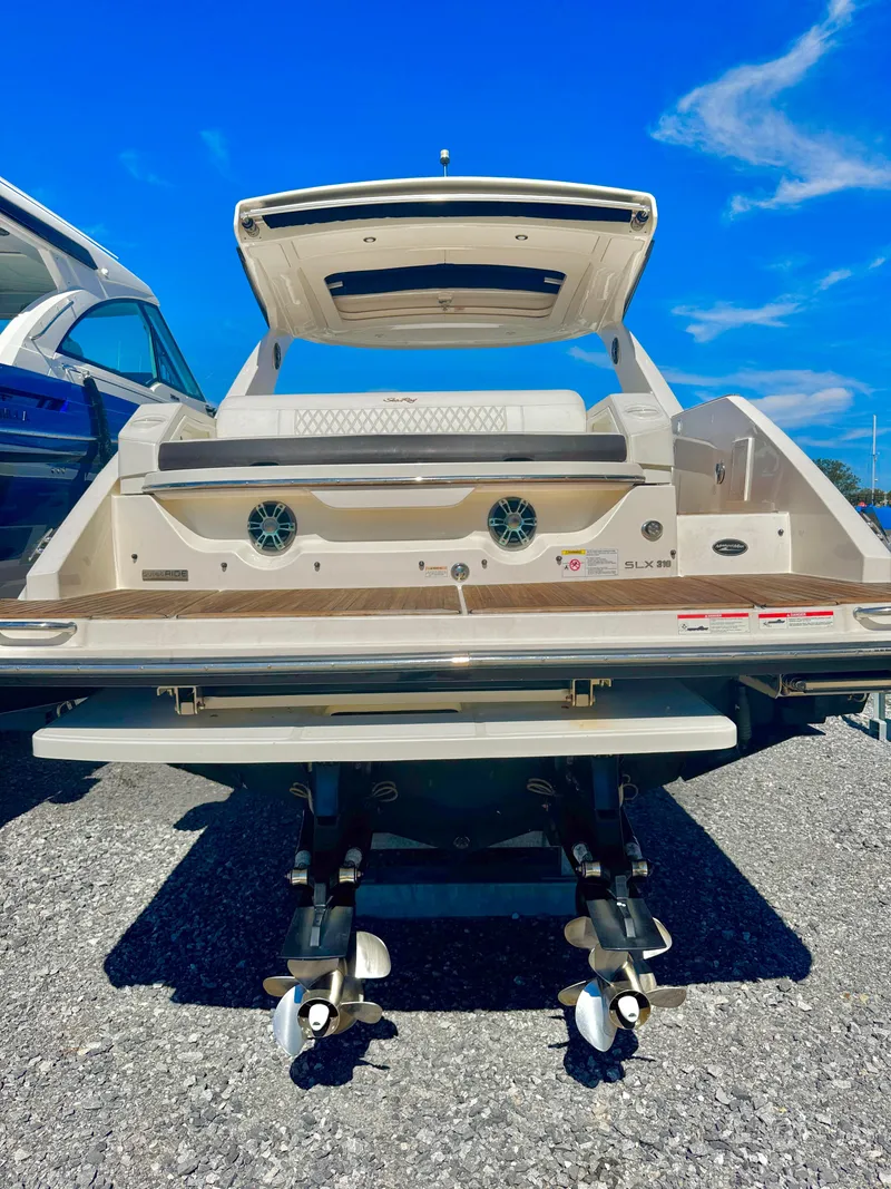 Slide: The Image of 2019 Sea Ray SLX 310 boat, rear view, showcasing swim platform and dual propellers under clear blue sky. - 39