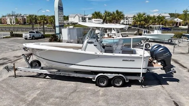 Slide: The Image of 2016 Regulator 25 boat on trailer, parked in a marina lot under clear skies. - 0