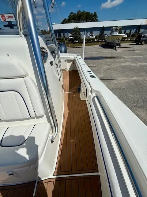 Slide: The Image of 2016 Regulator 25 boat with sleek deck and seating, parked outdoors. - 16