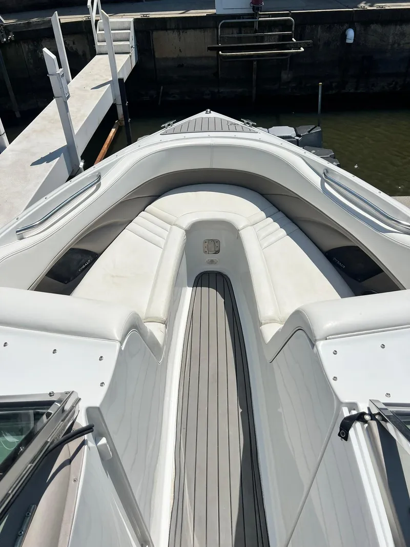 Slide: The Image of 2004 Cobalt 282 boat interior with white seating and wooden flooring at a dock. - 21