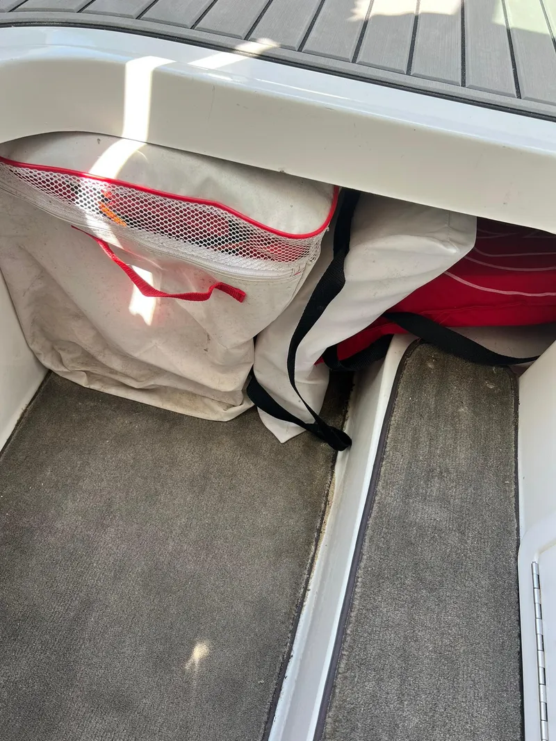 Slide: The Image of Storage compartment in a 2004 Cobalt 282 boat with bags and netting. - 28