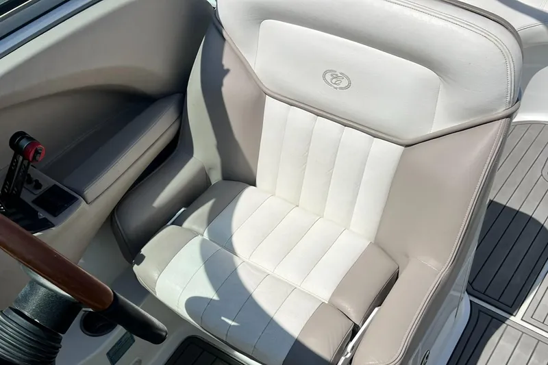 Slide: The Image of 2004 Cobalt 282 boat seat with beige and white upholstery, featuring a steering wheel and control panel. - 32