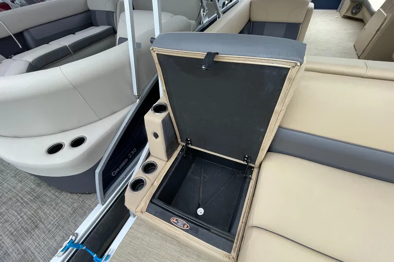 Slide: The Image of 2023 Harris Cruiser 230 boat interior with open storage compartment and cup holders. - 12