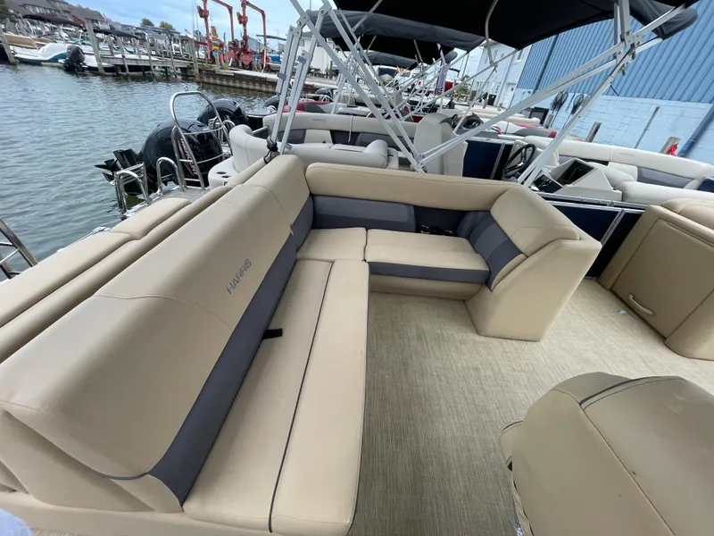Slide: The Image of 2023 Harris Cruiser 230 pontoon boat with beige seating at a marina. - 14