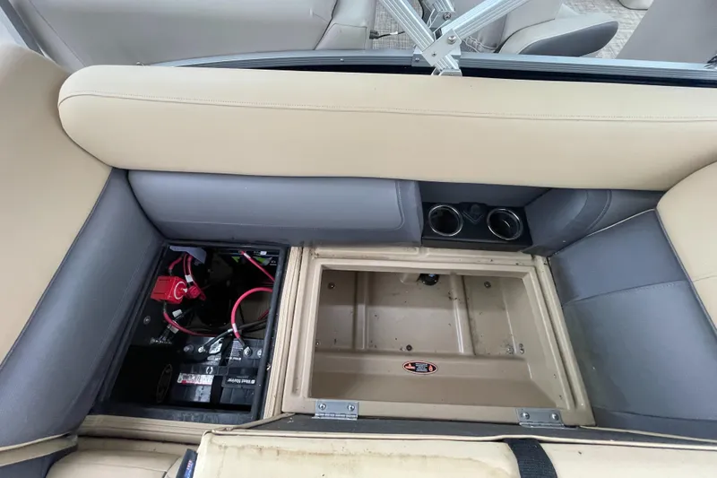 Slide: The Image of 2023 Harris Cruiser 230 interior storage and battery compartment with beige and gray seating. - 16