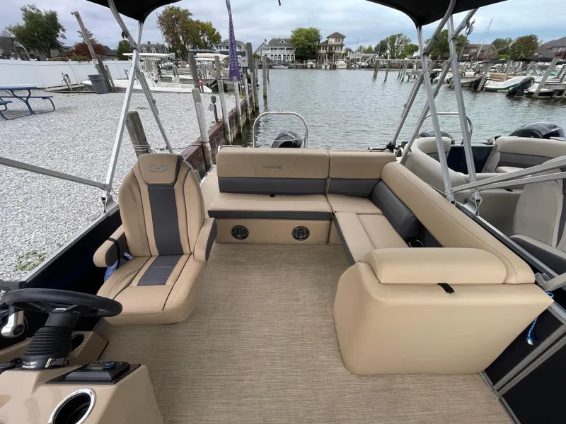 Slide: The Image of 2023 Harris Cruiser 230 pontoon boat interior with beige seating, docked at a marina. - 19