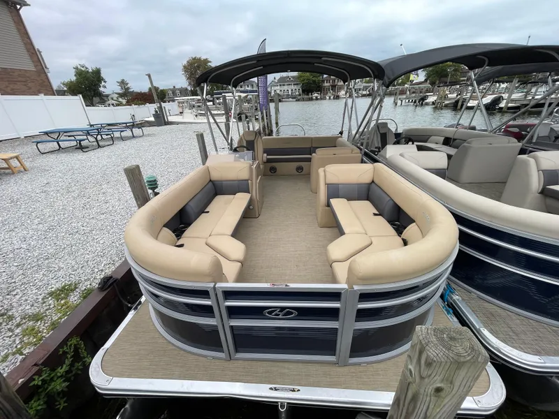 Slide: The Image of 2023 Harris Cruiser 230 pontoon boat docked at a marina, featuring spacious seating. - 2