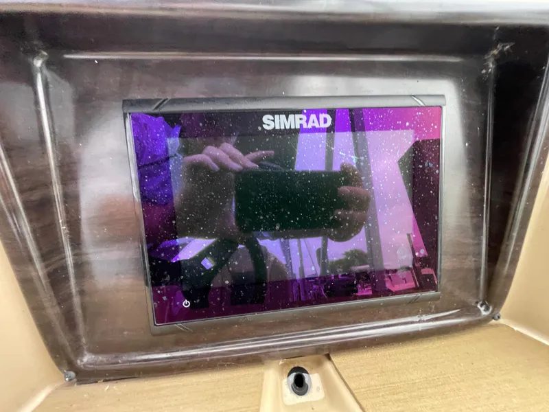 Slide: The Image of Simrad display on 2023 Harris Cruiser 230 boat dashboard, reflecting surroundings. - 26