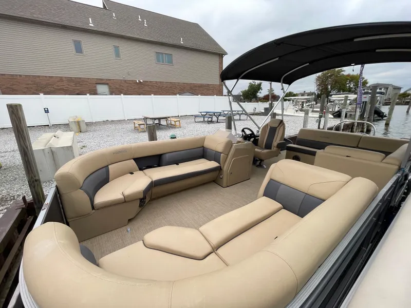 Slide: The Image of 2023 Harris Cruiser 230 pontoon boat with spacious seating and canopy, docked at a marina. - 3