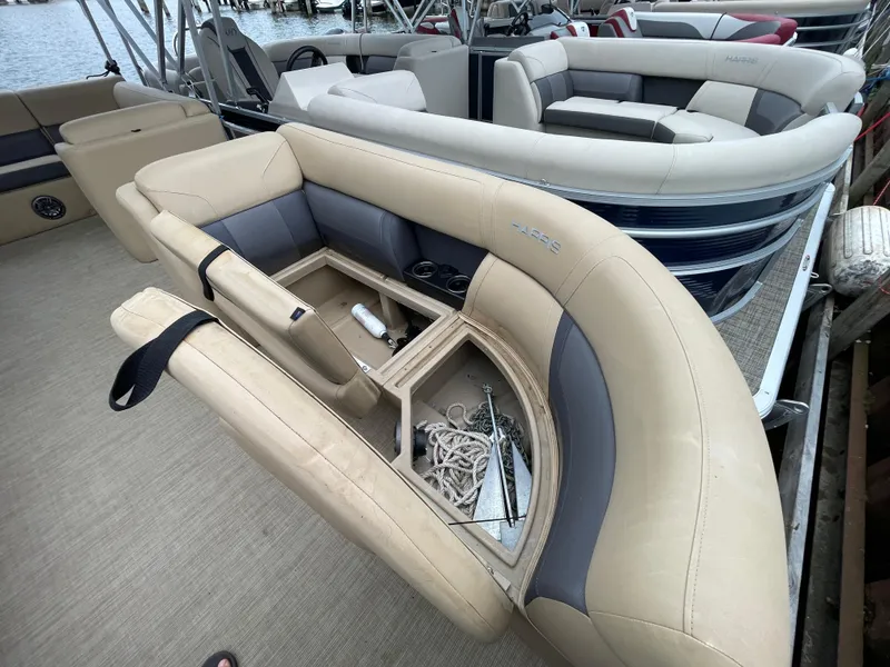 Slide: The Image of 2023 Harris Cruiser 230 boat interior with open storage compartment and beige seating. - 34