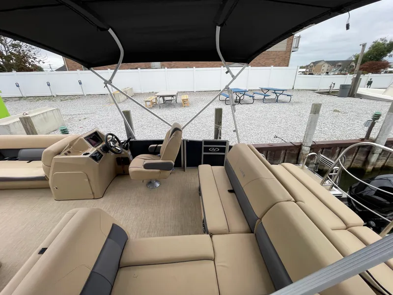 Slide: The Image of 2023 Harris Cruiser 230 pontoon boat interior with beige seating and black canopy. - 6