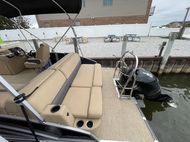 Slide: The Image of 2023 Harris Cruiser 230 pontoon boat with beige seating and outboard motor docked at marina. - 7