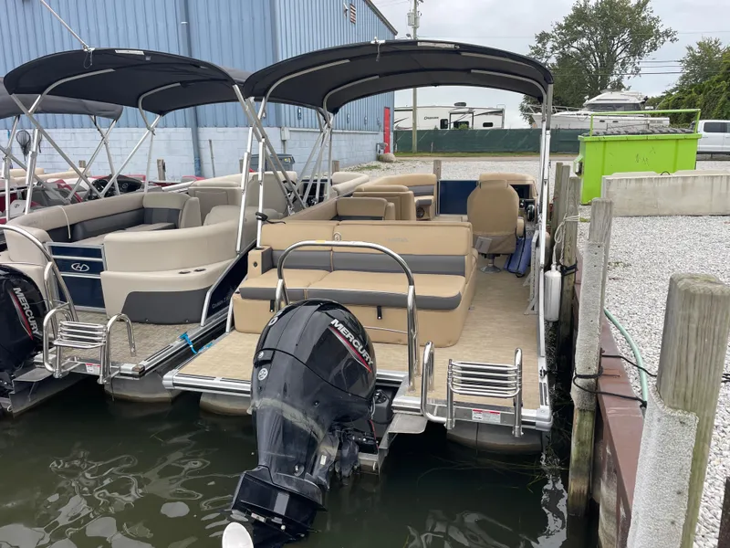 Slide: The Image of 2023 Harris Cruiser 230 pontoon boat docked with outboard motor and canopy. - 8