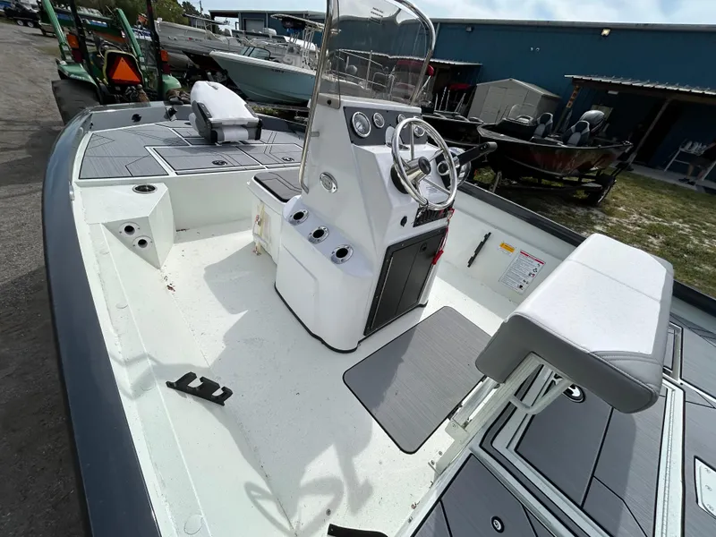 Slide: The Image of 2025 Crestliner 1800 Bay boat interior with steering console and seating, docked outdoors. - 13