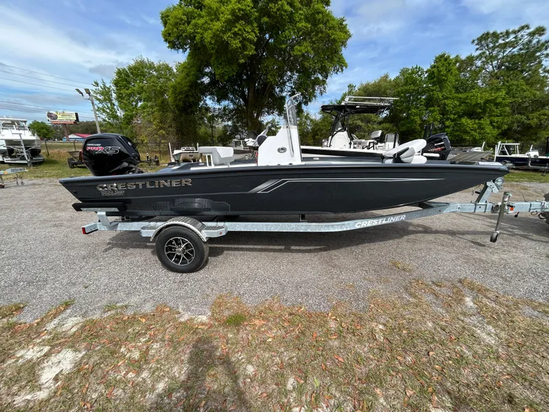 Slide: The Image of 2025 Crestliner 1800 Bay boat on trailer, parked outdoors with trees in the background. - 4