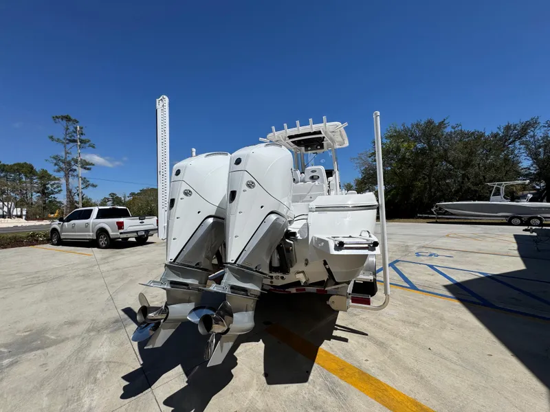 Slide: The Image of 2025 Caymas 291 boat with dual outboard motors in a sunny parking lot. - 15