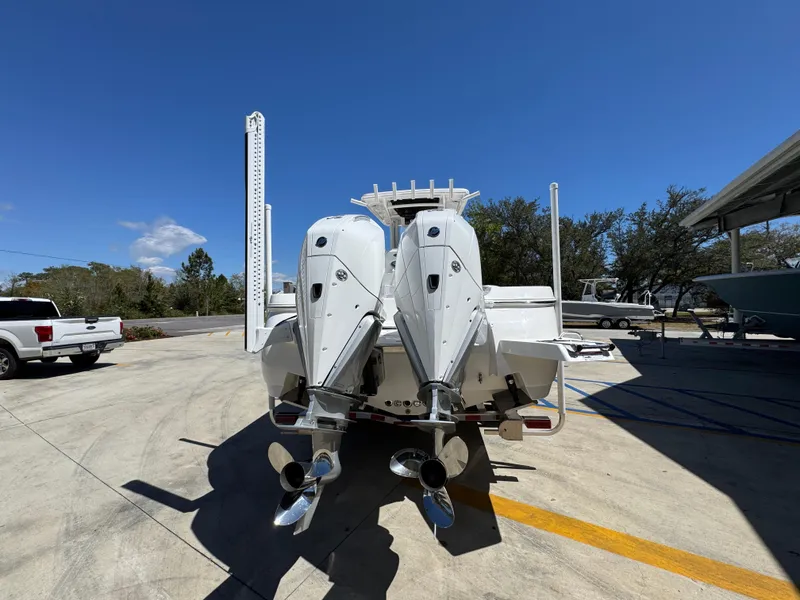 Slide: The Image of 2025 Caymas 291 boat with dual outboard motors, parked outdoors under clear blue sky. - 16