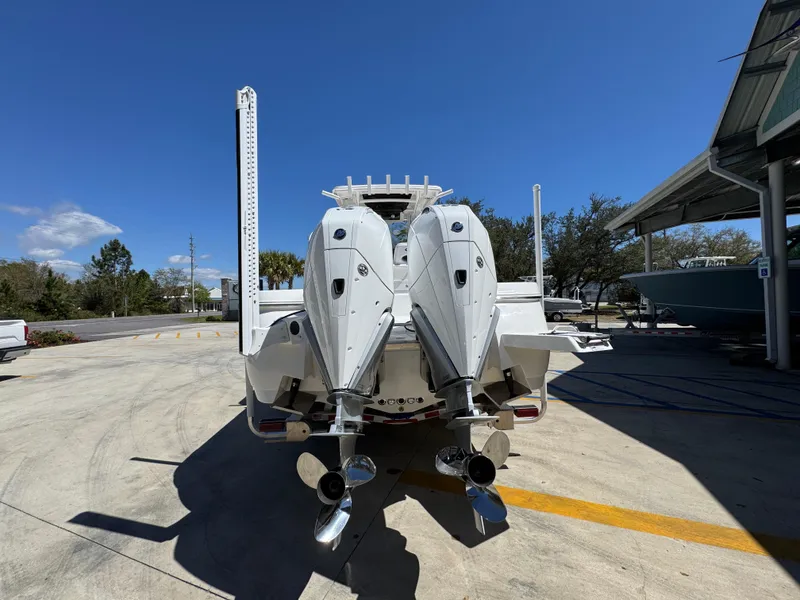 Slide: The Image of 2025 Caymas 291 boat with dual outboard engines, parked outdoors under clear blue sky. - 17