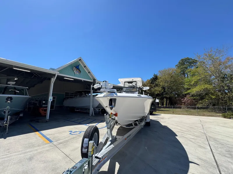 Slide: The Image of 2025 Caymas 291 boat on trailer outside a garage under clear blue sky. - 6