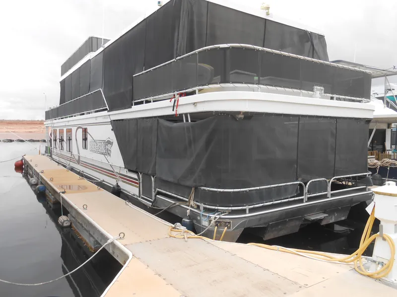 Slide: The Image of 2008 Sumerset 7518 houseboat docked with black coverings, side view. - 1