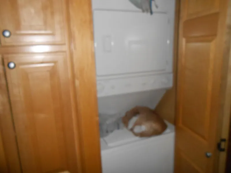 Slide: The Image of Laundry area with wooden cabinets and a stacked washer-dryer in a 2008 Sumerset 7518. - 6