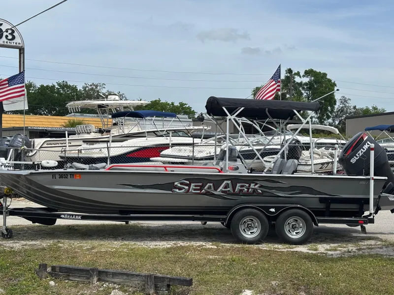 Slide: The Image of 2019 SeaArk Big Easy boat on trailer, parked with American flags in background. - 2
