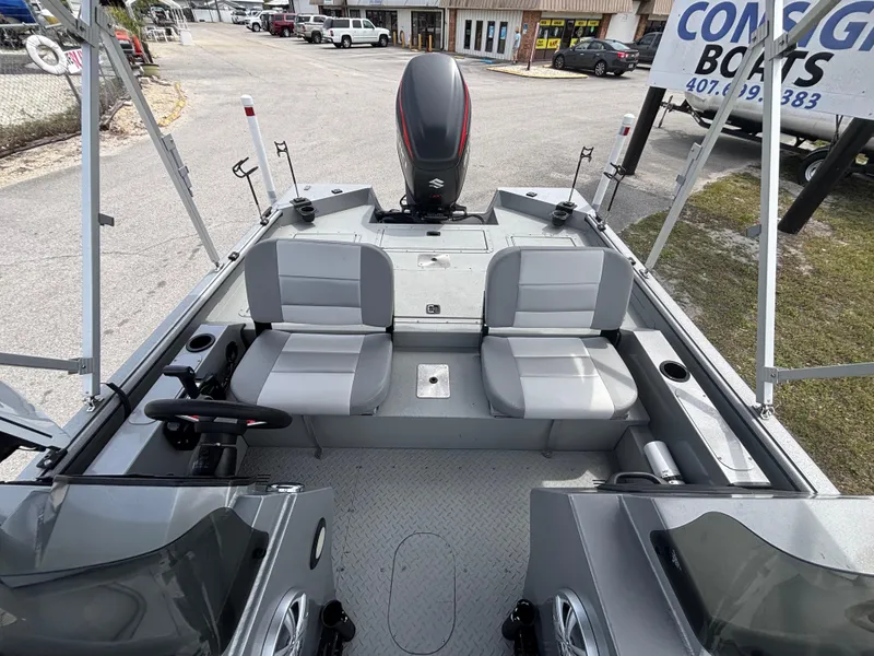 Slide: The Image of 2019 SeaArk Big Easy boat interior with seating and motor, parked near a boat dealership. - 30