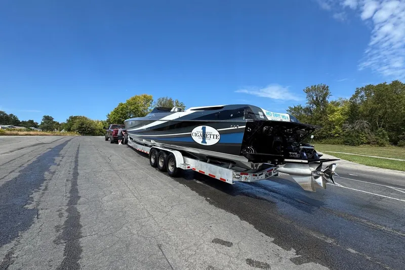 Slide: The Image of 2011 Cigarette 50' Marauder boat on trailer, parked on a road under clear blue sky. - 9
