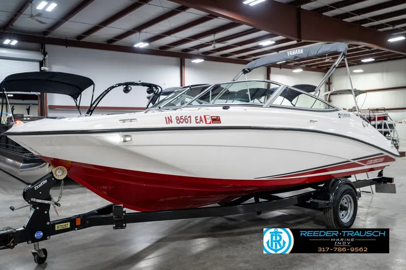 Slide: The Image of 2018 Yamaha SX190 boat with red and white design on a trailer in a showroom. - 2