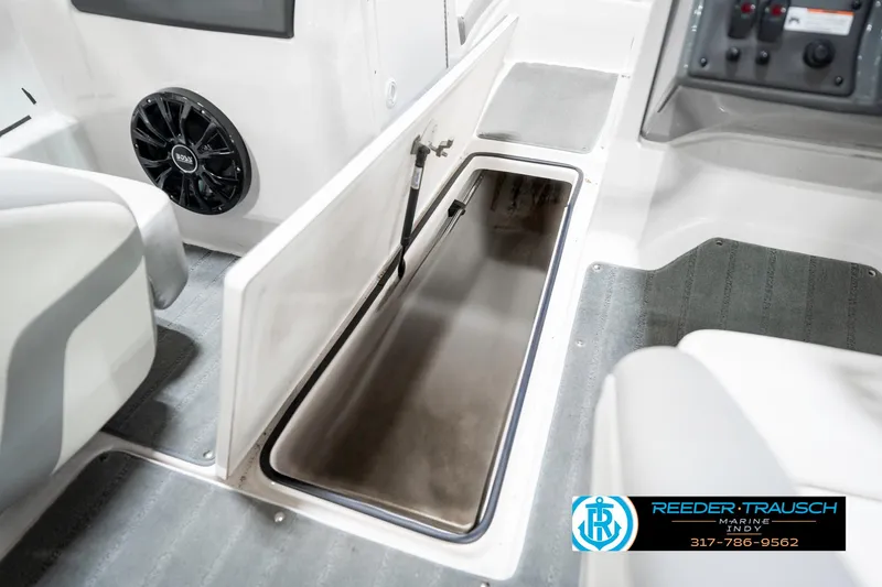 Slide: The Image of 2018 Yamaha Boats SX190 interior storage compartment with open hatch, gray flooring, and speaker. - 27