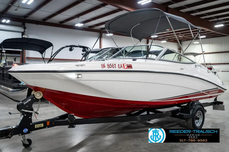 Slide: The Image of 2018 Yamaha SX190 boat with red hull and canopy in indoor showroom. - 3