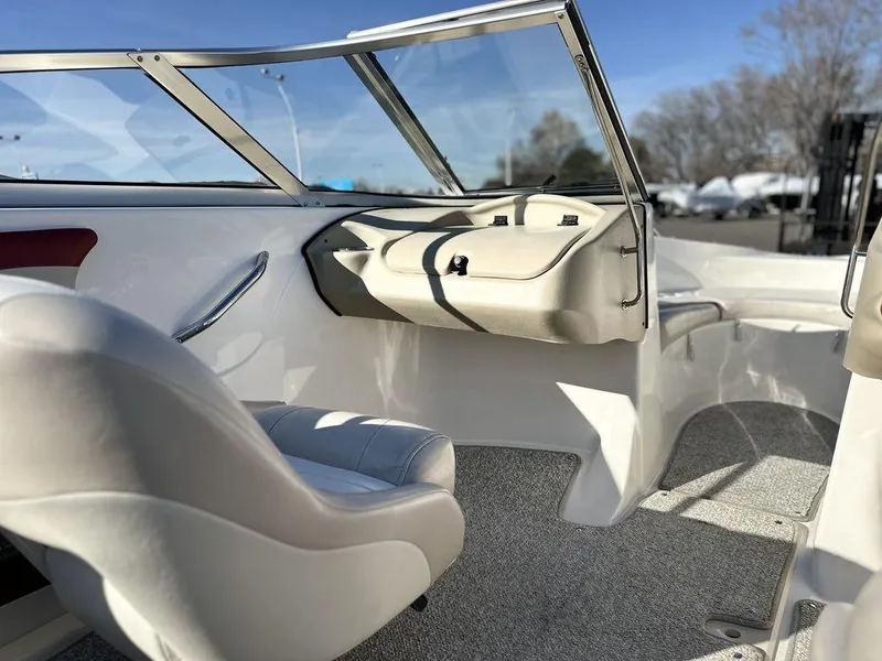 Slide: The Image of 2007 Glastron GT 185 boat interior with white seating and windshield, under clear blue sky. - 7