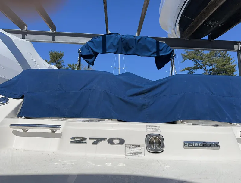Slide: The Image of 2013 Sea Ray 270 SLX boat with blue cover, docked under clear sky. - 25