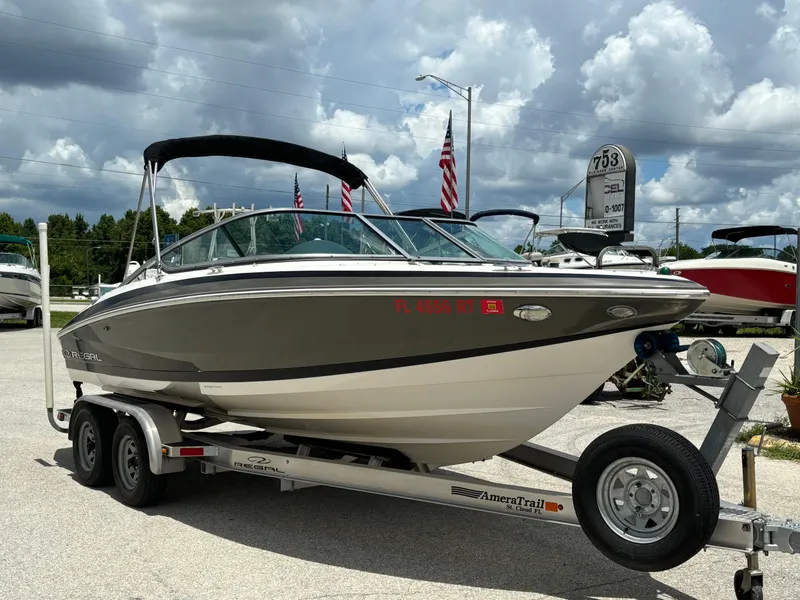 Slide: The Image of 2016 Regal 2100 RX Bowrider on trailer, parked outdoors under cloudy sky. - 1