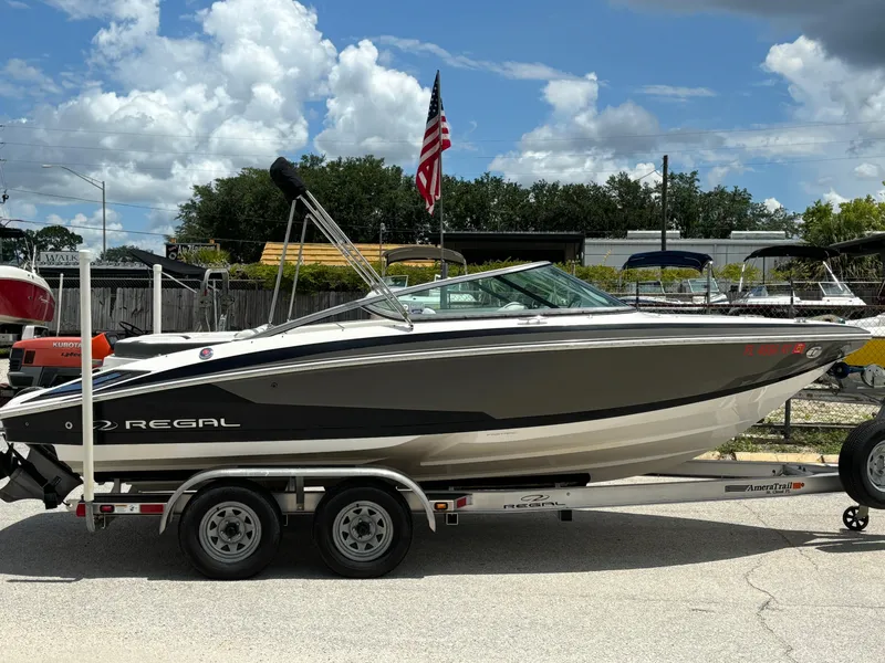Slide: The Image of 2016 Regal 2100 RX Bowrider on trailer, parked outdoors under a cloudy sky. - 2