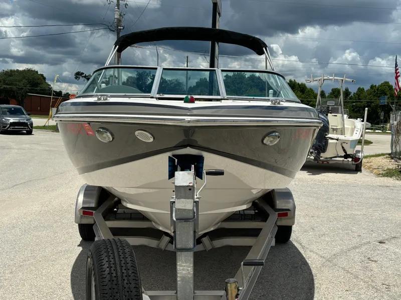 Slide: The Image of 2016 Regal 2100 RX Bowrider on trailer, parked outdoors under cloudy sky. - 3